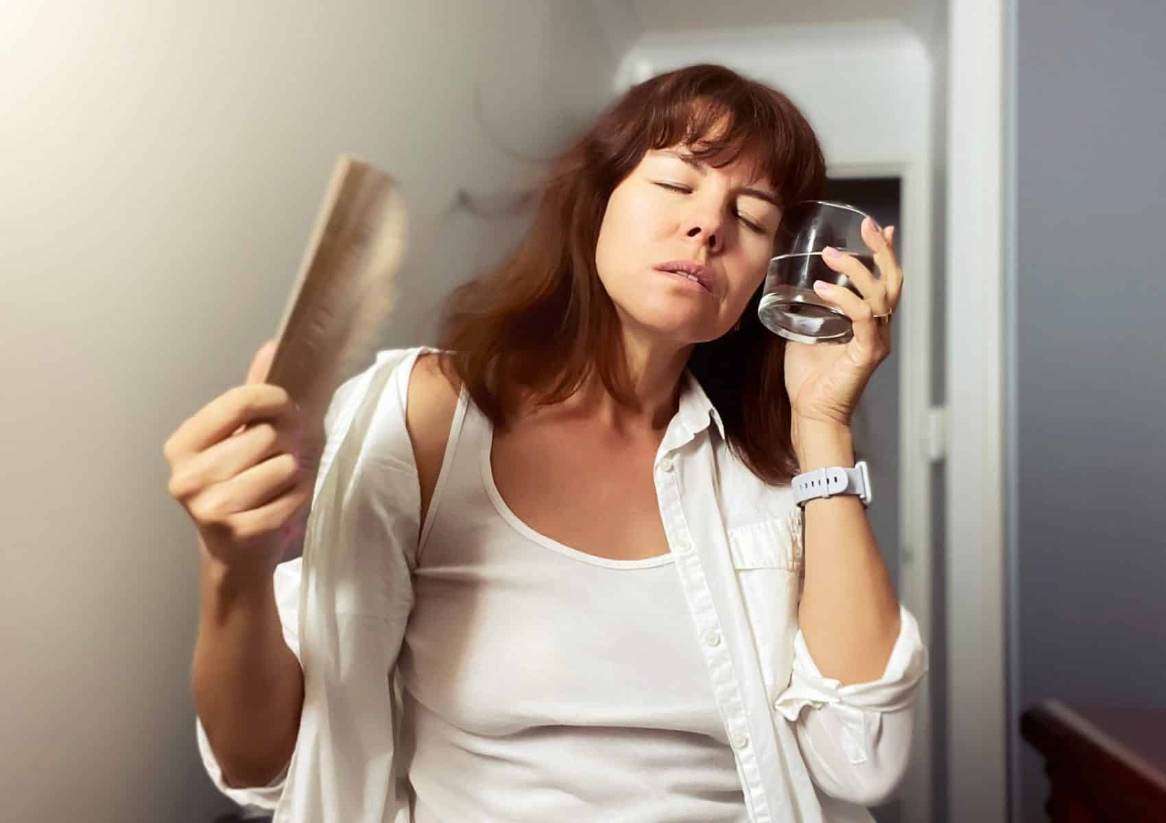 A woman cooling down with a fan and glass of water