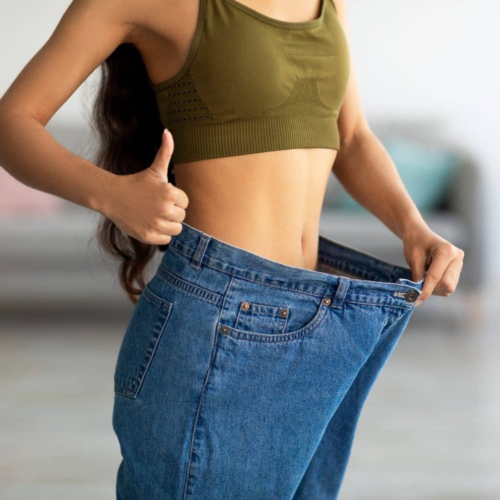 femme dans son ancien jean devenu trop grand après avoir perdu du poids