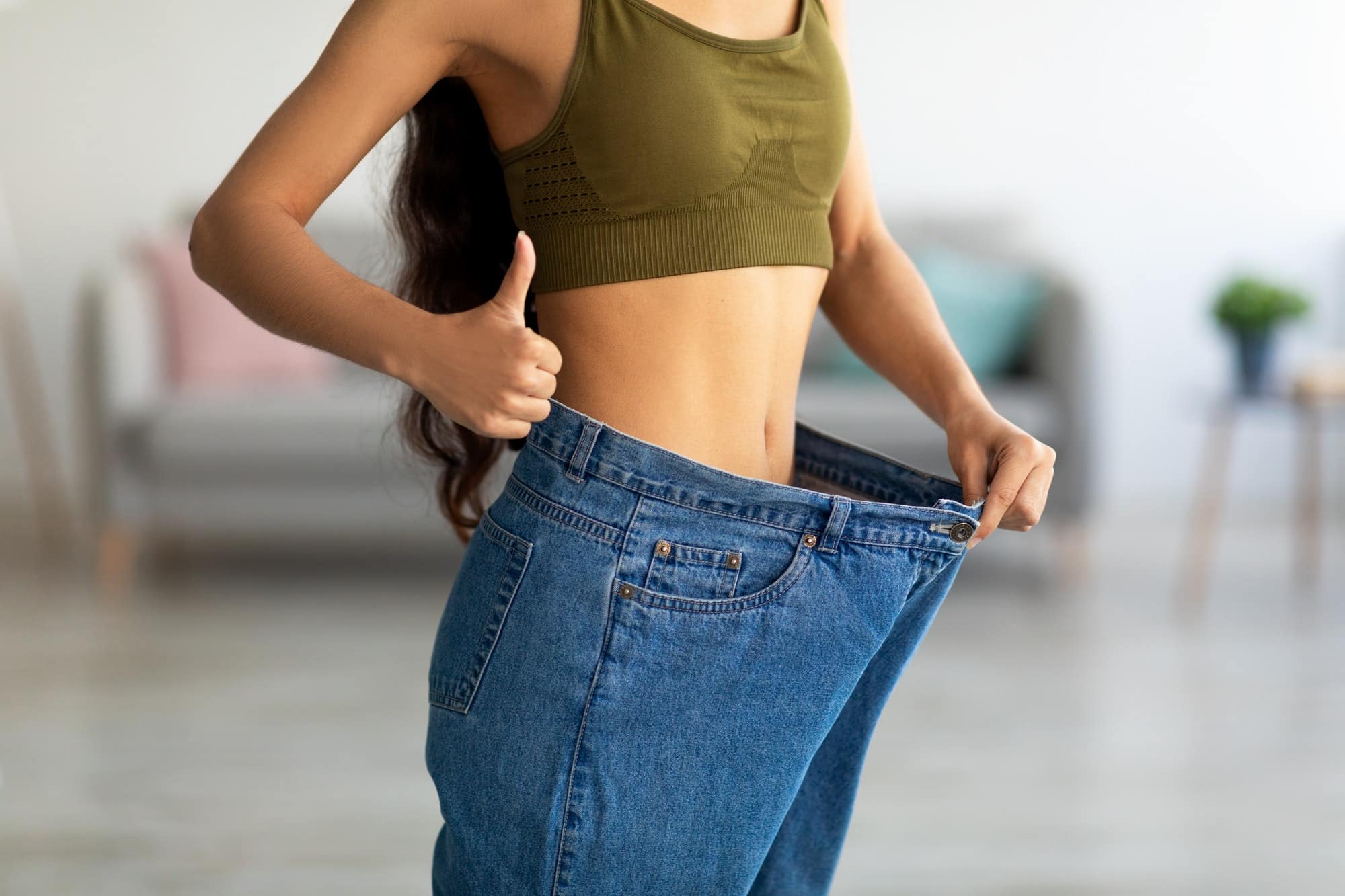 femme dans son ancien jean devenu trop grand après avoir perdu du poids