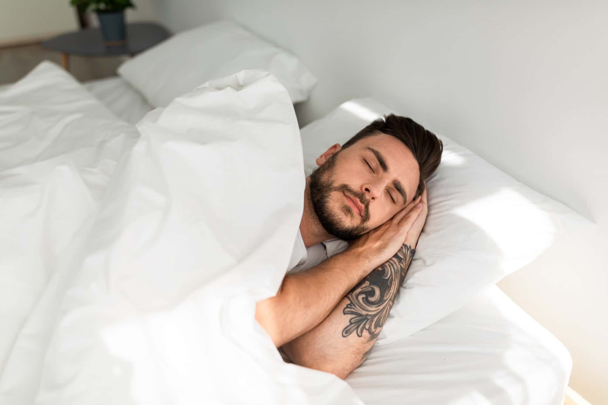 homme tatoué dort dans son lit