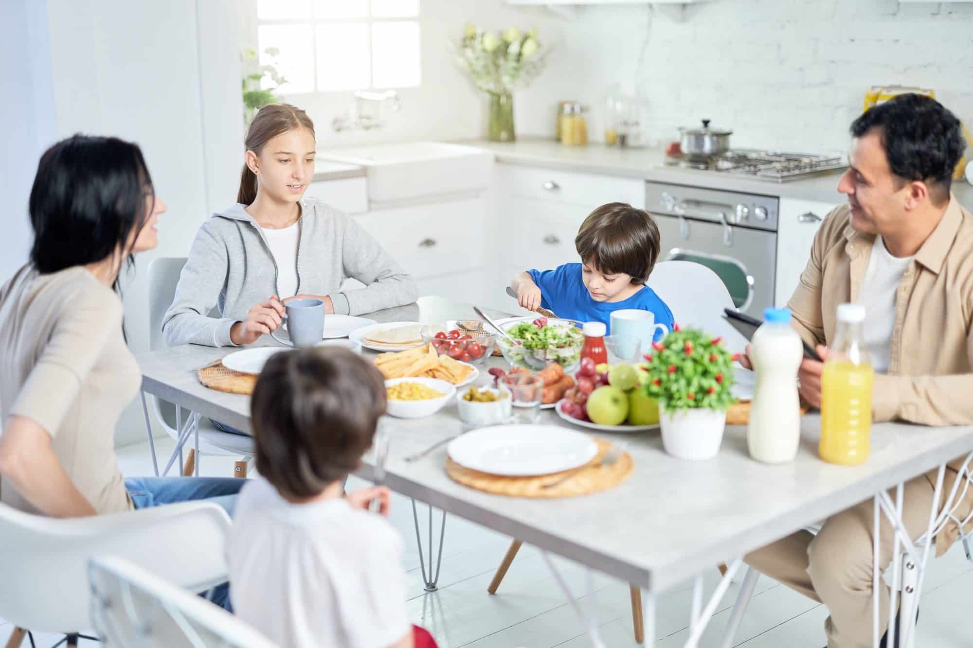Eat and enjoy. Happy latin family enjoying meal together, sitting at the table in kitchen at home