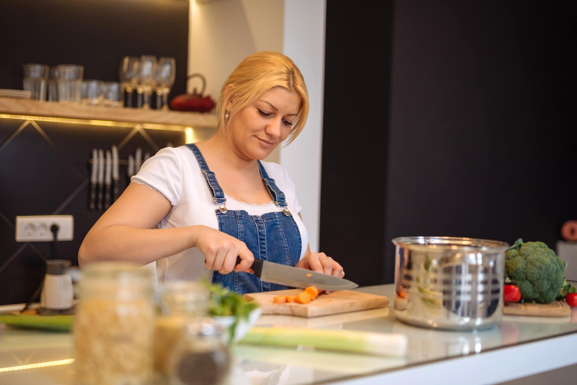 femme coupe une carotte et cuisine un repas sain et équilibré