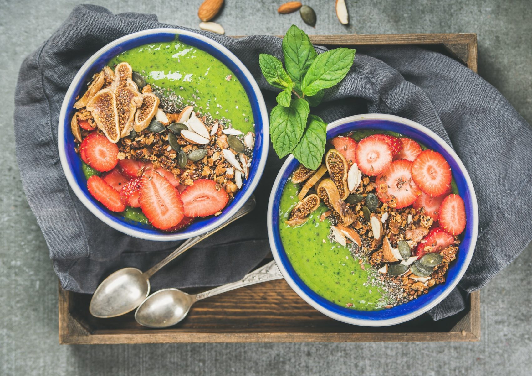 Healthy green smoothie breakfast bowls with granola, fruit, seeds, berries