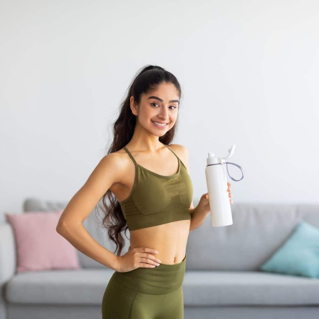 femme en vêtements de sport tient une gourde dans la main 