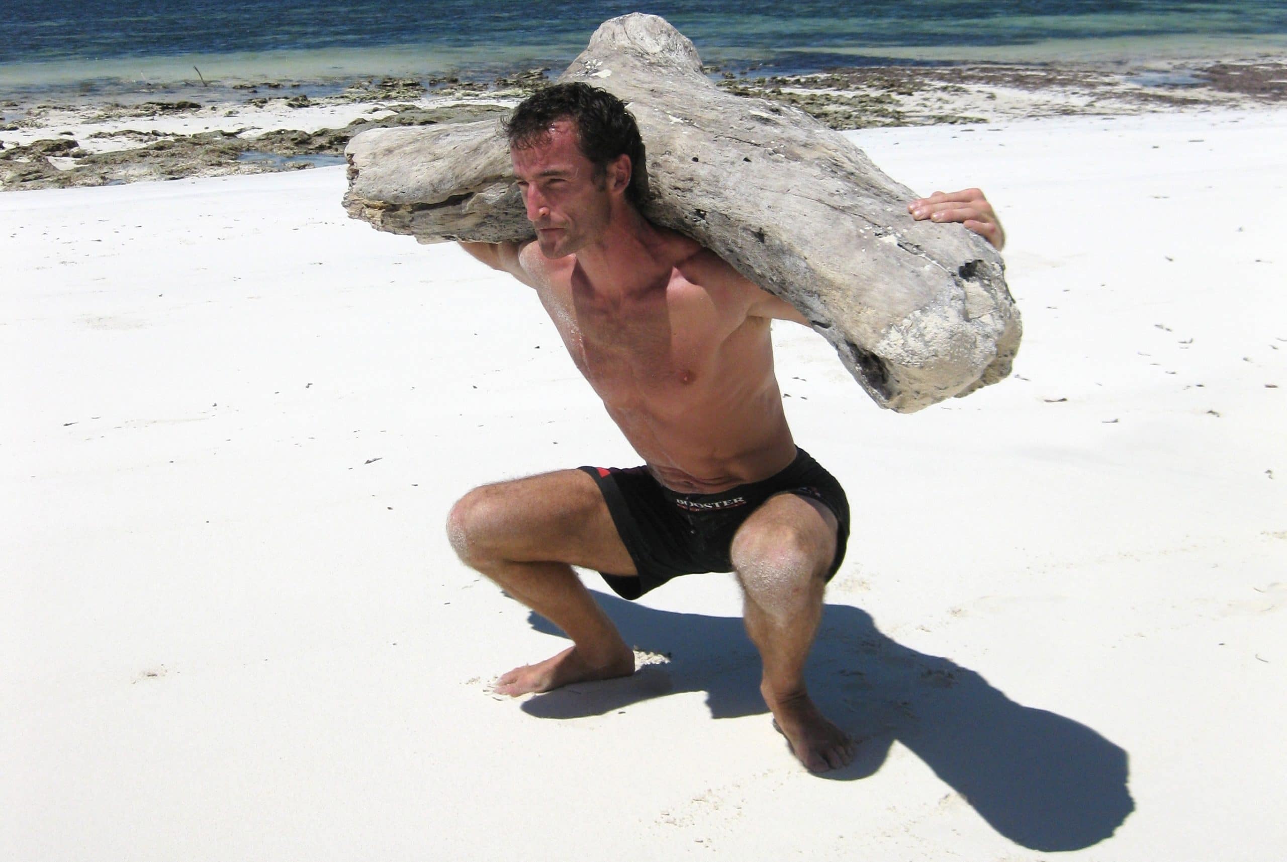 MovNat creator Erwan Le Corre squatting on the beach.