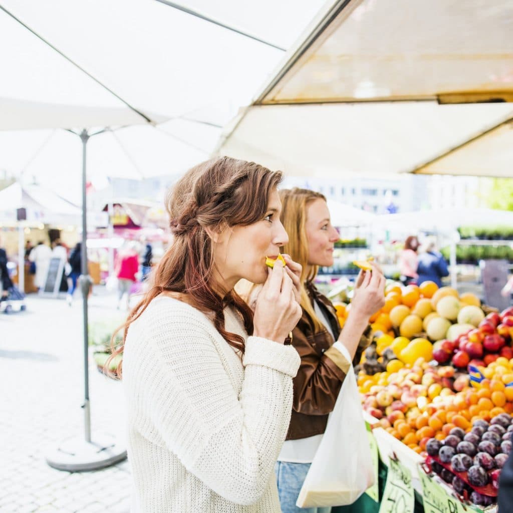 deux femmes mangent des fruits au marché