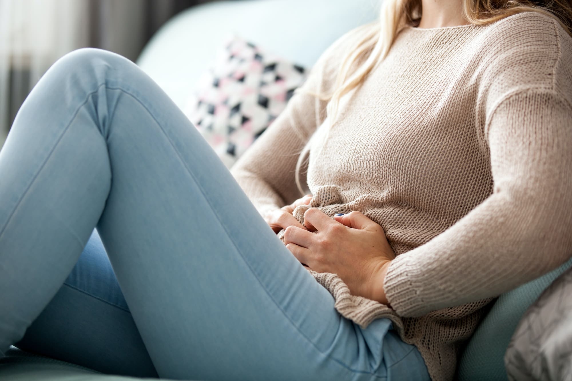 femme sur son sofa a mal au ventre